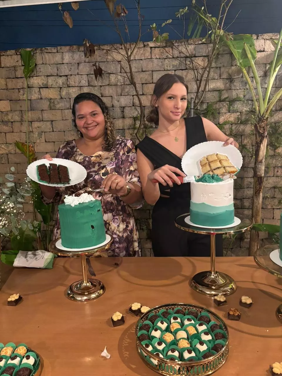 Clara Finelon ao lado de uma aluna, ambas mostrando fatias de bolo